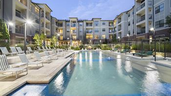 An apartment building with a swimming pool and lounge chairs
